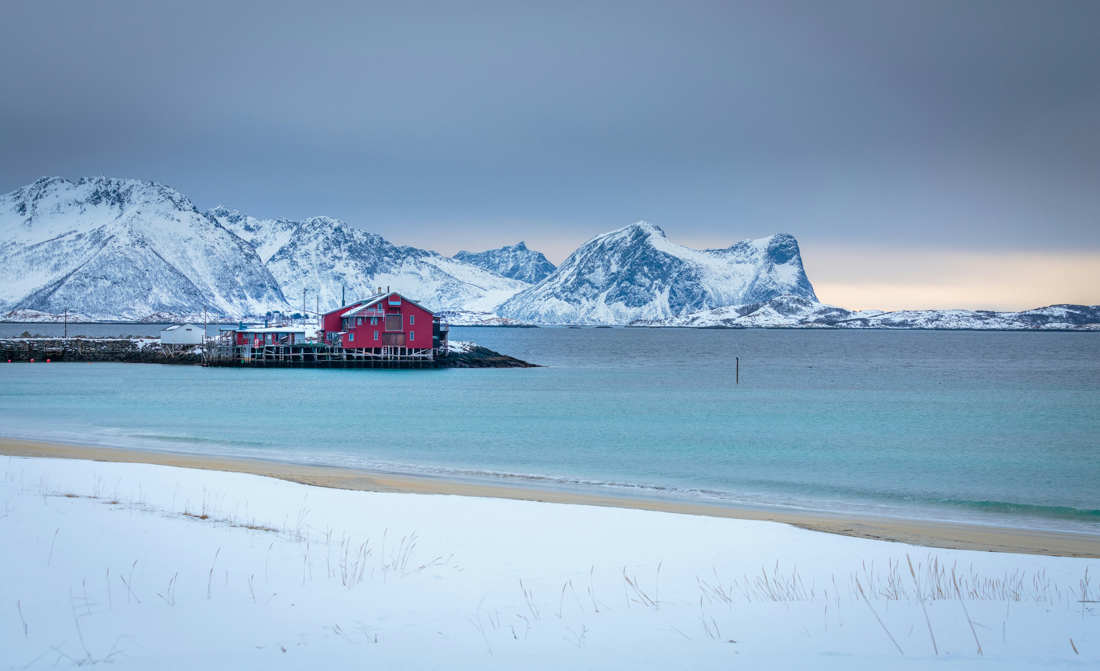 red and white house near body of water and snow covered mountain during daytime